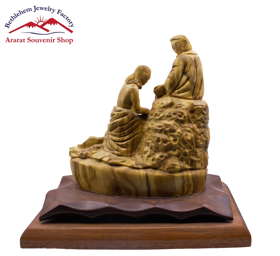 A statue of Jesus washes the disciples' feet on a wooden base.