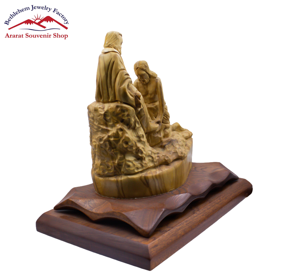 A statue of Jesus washes the disciples' feet on a wooden base stands as a symbol of faith.